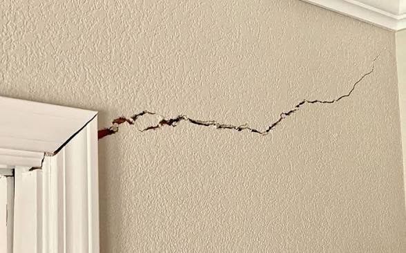 A jagged drywall crack radiating from a door frame, a common sign of foundation movement in North Texas homes
